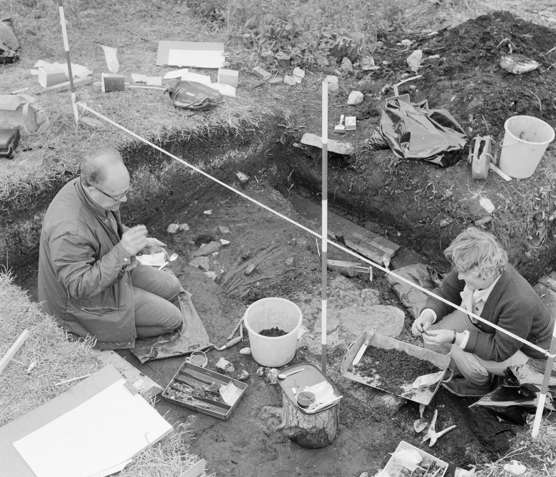 two archaeologists sitting in a trench