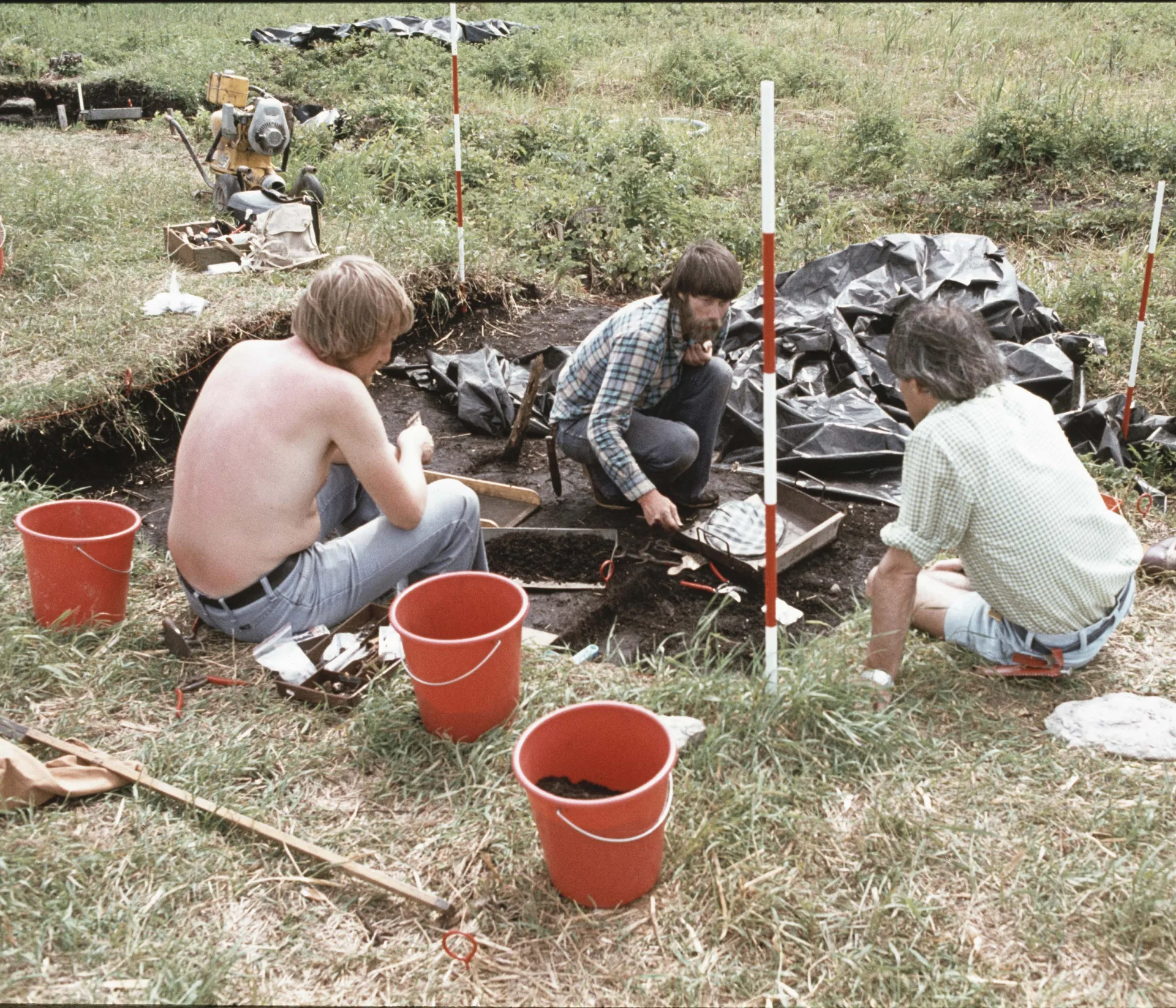 Image from an on-going excavation with three people sitting in a hole